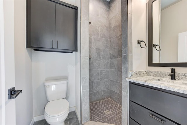 full bath featuring baseboards, toilet, tiled shower, tile patterned floors, and vanity