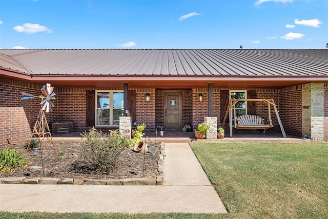 view of front of house featuring metal roof, brick siding, and a front yard