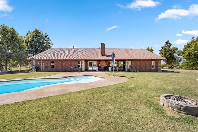 outdoor pool with a yard, a patio area, and a fire pit