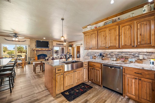 kitchen with a peninsula, a fireplace, a sink, dishwasher, and backsplash