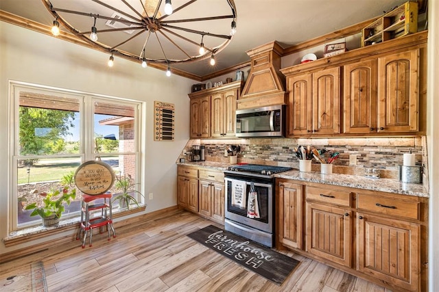 kitchen featuring stainless steel appliances, backsplash, ornamental molding, and light wood-style flooring