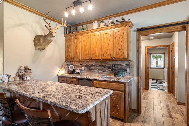 kitchen with a breakfast bar, a peninsula, a sink, light wood-style floors, and tasteful backsplash