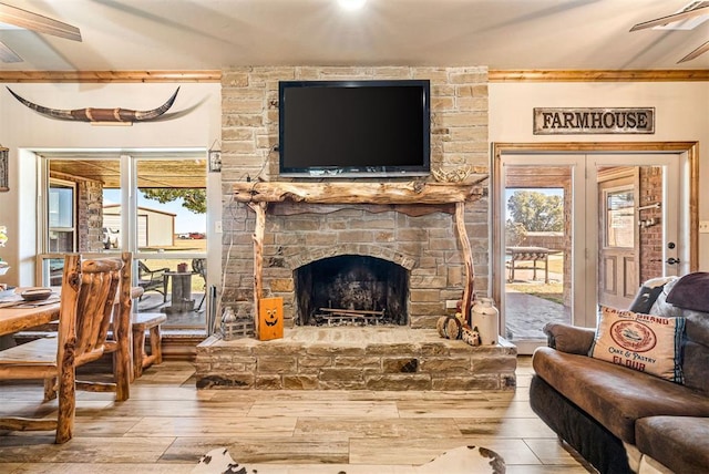 living area featuring a stone fireplace, wood finished floors, and ceiling fan