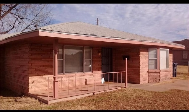 view of front of home featuring brick siding and a shingled roof