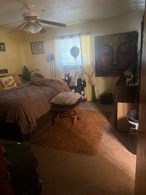 carpeted bedroom featuring ceiling fan and a textured ceiling