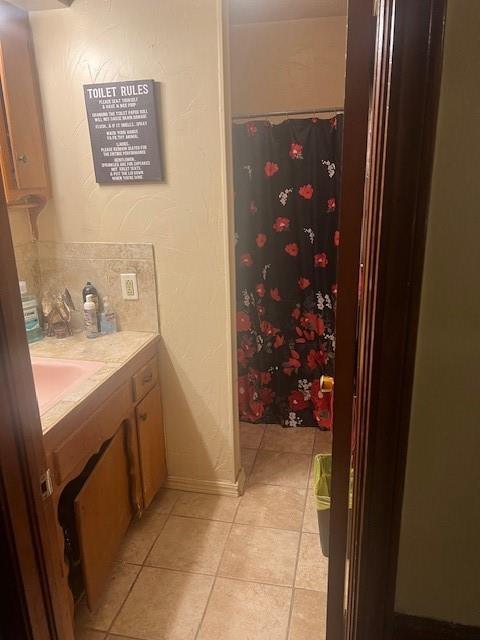 bathroom featuring baseboards, a shower with shower curtain, tile patterned flooring, and vanity