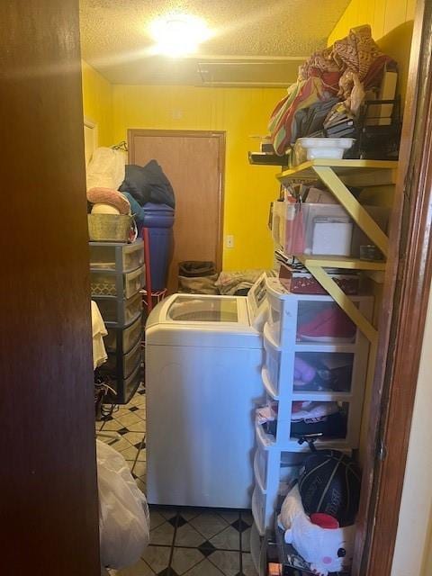 clothes washing area featuring laundry area, washing machine and clothes dryer, a textured ceiling, and tile patterned floors