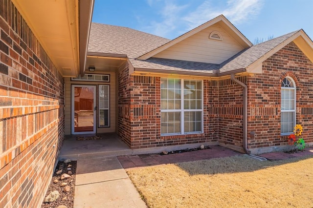 property entrance with brick siding and a shingled roof