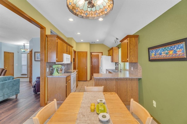 kitchen with tasteful backsplash, light countertops, vaulted ceiling, white appliances, and a sink