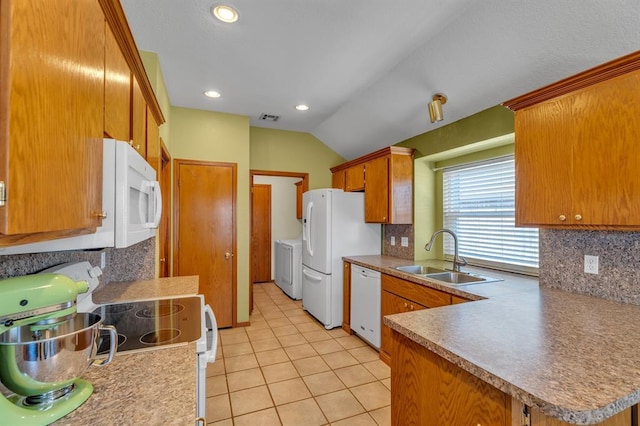 kitchen with white appliances, brown cabinetry, light tile patterned flooring, a sink, and washer and dryer