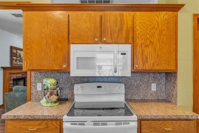 kitchen with decorative backsplash, white appliances, visible vents, and brown cabinets