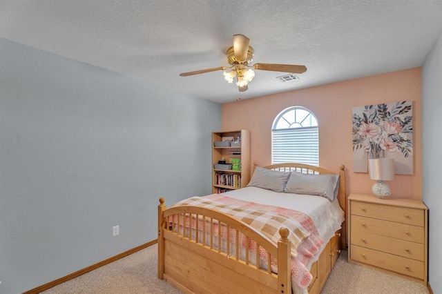 bedroom with baseboards, visible vents, ceiling fan, a textured ceiling, and light colored carpet