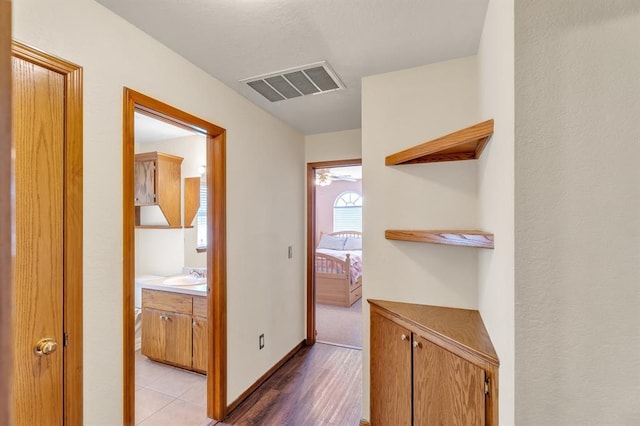 corridor featuring a sink, visible vents, and baseboards