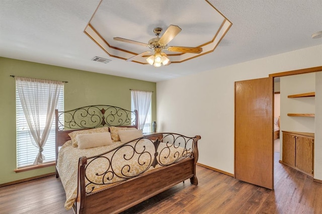 bedroom with visible vents, baseboards, a textured ceiling, and wood finished floors