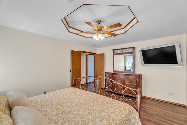 bedroom featuring baseboards, wood finished floors, and a ceiling fan