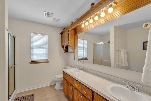 bathroom featuring tile patterned flooring, a stall shower, visible vents, and a sink