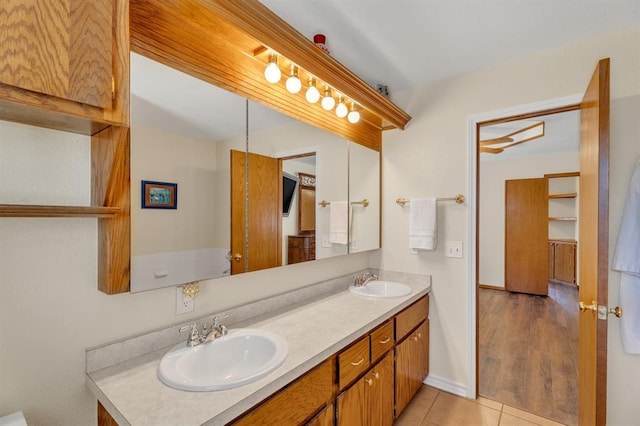 full bathroom featuring a sink, baseboards, double vanity, and tile patterned floors