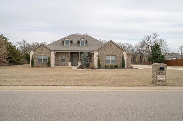 view of front of house with brick siding, a front lawn, and roof with shingles