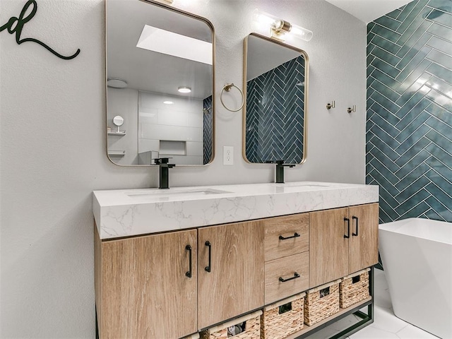 full bathroom featuring a sink, a freestanding tub, tile walls, and double vanity