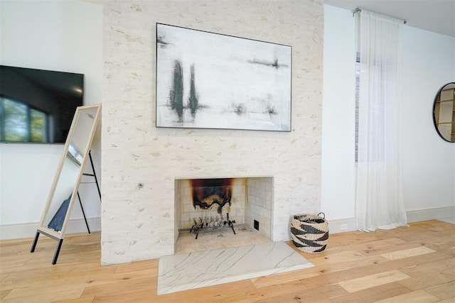 living room with wood finished floors, baseboards, and a large fireplace