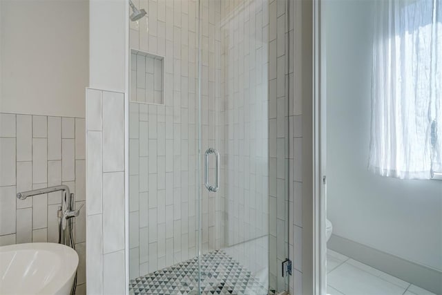 bathroom with toilet, tile walls, a shower stall, and tile patterned flooring