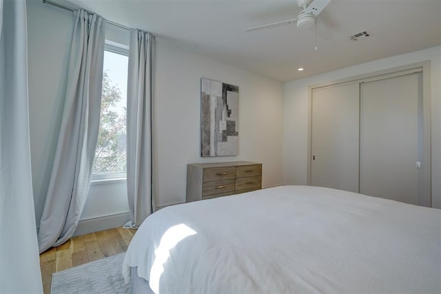 bedroom featuring visible vents, multiple windows, light wood-style flooring, and a ceiling fan