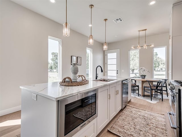 12 S Howard St, Edmond, OK 73003 - kitchen featuring visible vents, light stone counters, appliances with stainless steel finishes, white cabinets, and a sink