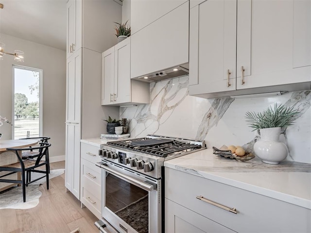 12 S Howard St, Edmond, OK 73003 - kitchen with high end stove, tasteful backsplash, white cabinetry, ventilation hood, and light wood finished floors