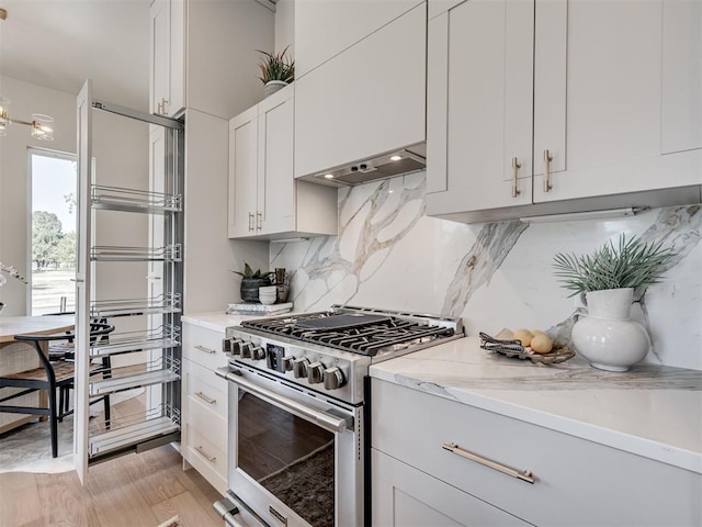 12 S Howard St, Edmond, OK 73003 - kitchen featuring backsplash, stainless steel stove, white cabinets, light stone countertops, and extractor fan