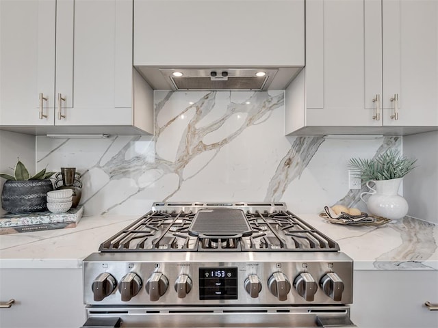 12 S Howard St, Edmond, OK 73003 - kitchen with stainless steel gas range oven, backsplash, white cabinets, exhaust hood, and light stone countertops