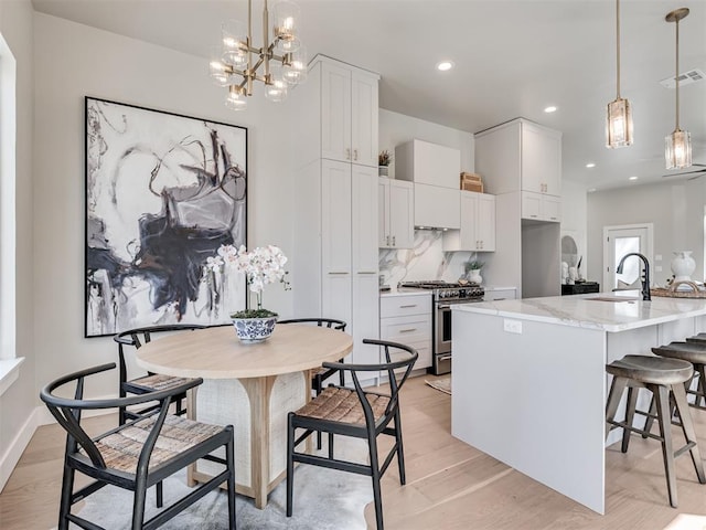 12 S Howard St, Edmond, OK 73003 - kitchen featuring visible vents, a sink, decorative backsplash, stainless steel range, and light wood-type flooring