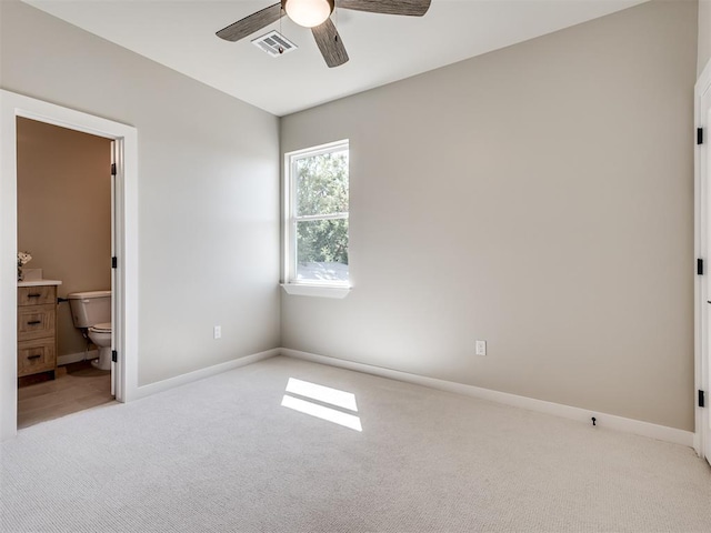 12 S Howard St, Edmond, OK 73003 - unfurnished bedroom with visible vents, baseboards, light carpet, ensuite bath, and a ceiling fan