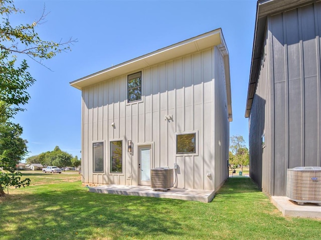 12 S Howard St, Edmond, OK 73003 - rear view of property featuring a yard, board and batten siding, and central AC unit