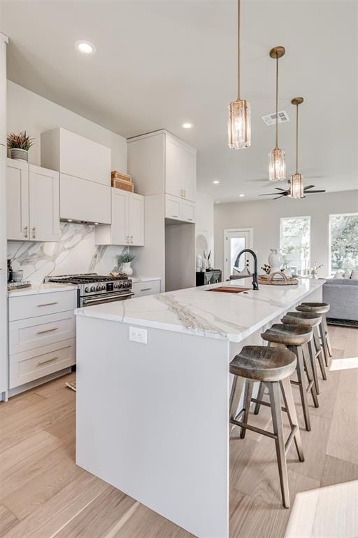 12 S Howard St, Edmond, OK 73003 - kitchen featuring tasteful backsplash, visible vents, light stone countertops, high end stainless steel range oven, and a sink