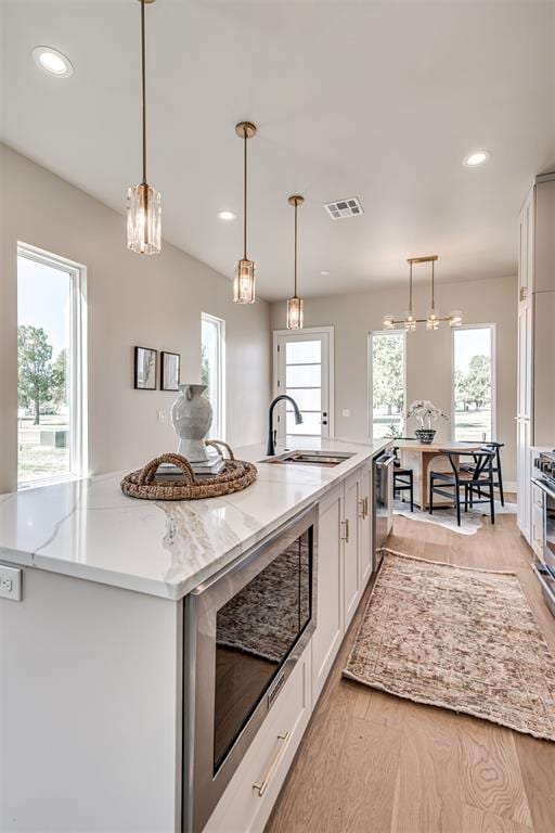 12 S Howard St, Edmond, OK 73003 - kitchen featuring a sink, visible vents, light stone countertops, and a healthy amount of sunlight