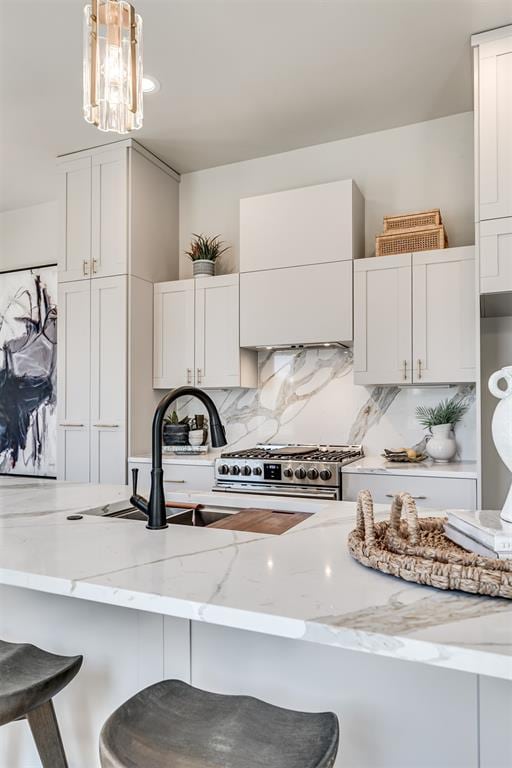 12 S Howard St, Edmond, OK 73003 - kitchen featuring light stone countertops, decorative backsplash, stainless steel range, white cabinets, and a kitchen bar
