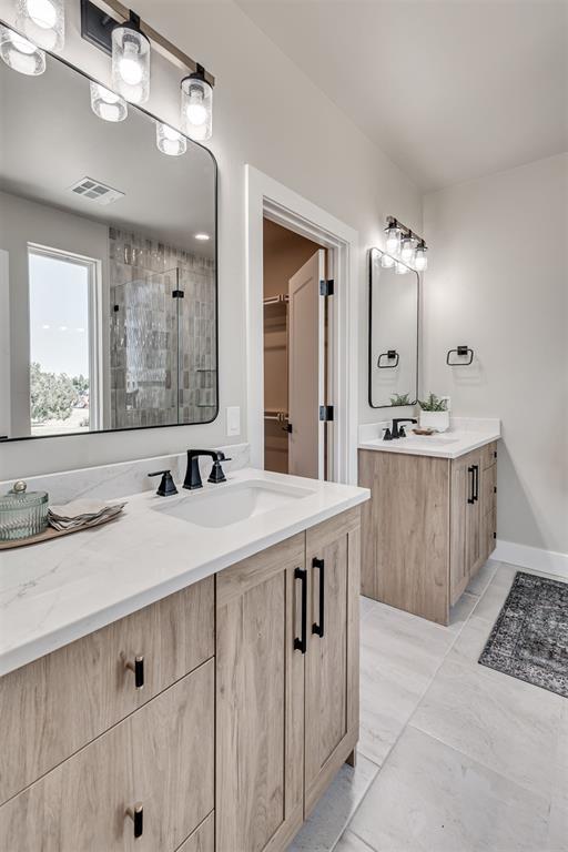 12 S Howard St, Edmond, OK 73003 - bathroom featuring visible vents, two vanities, a stall shower, a sink, and a spacious closet