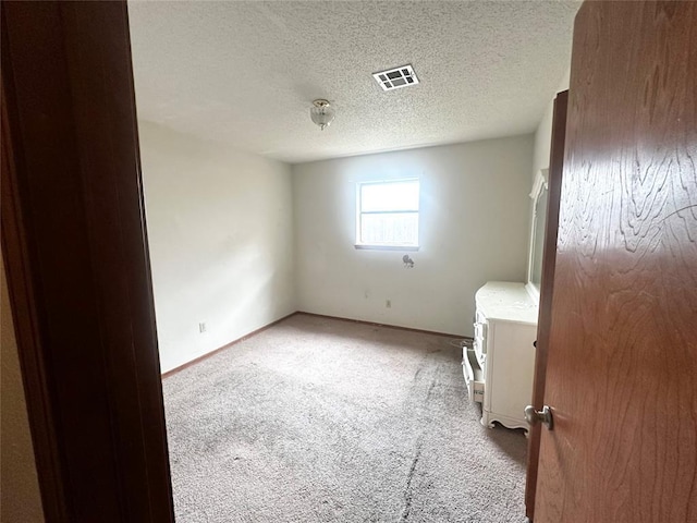 empty room with visible vents, baseboards, light colored carpet, and a textured ceiling