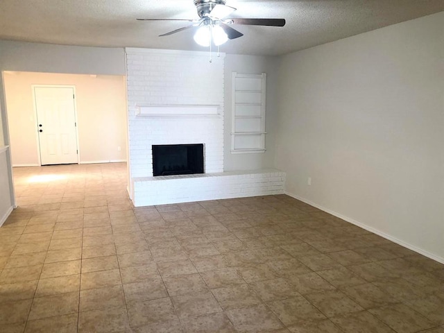 unfurnished living room with baseboards, a brick fireplace, a textured ceiling, and ceiling fan