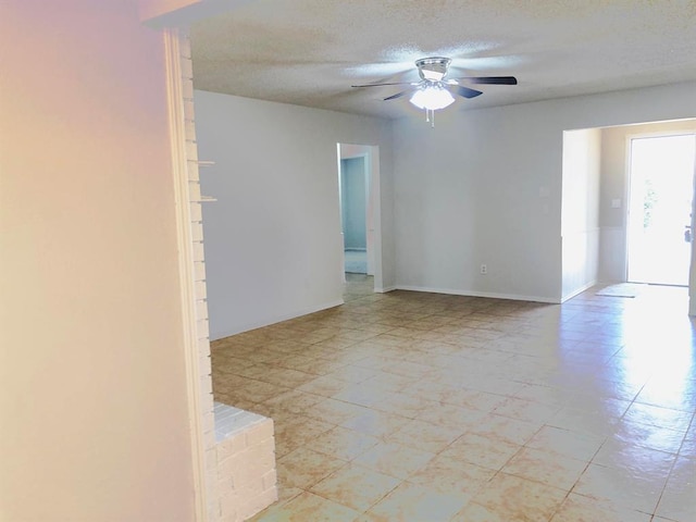 spare room featuring baseboards, a textured ceiling, and a ceiling fan