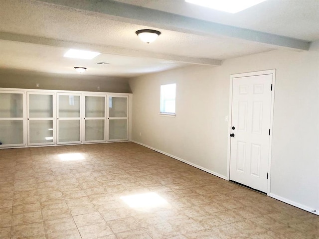 spare room with beam ceiling, tile patterned floors, a textured ceiling, and baseboards