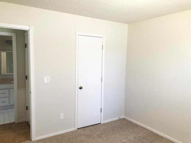 unfurnished bedroom with a textured ceiling, baseboards, and carpet floors