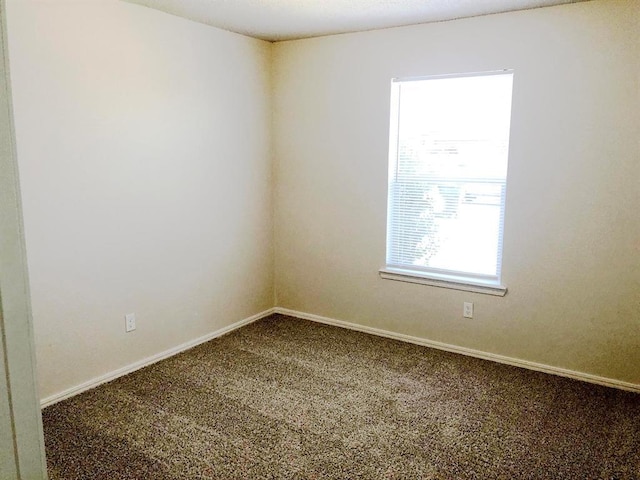 carpeted spare room featuring baseboards