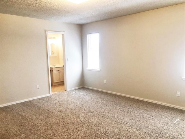 spare room featuring a textured ceiling, baseboards, and light carpet