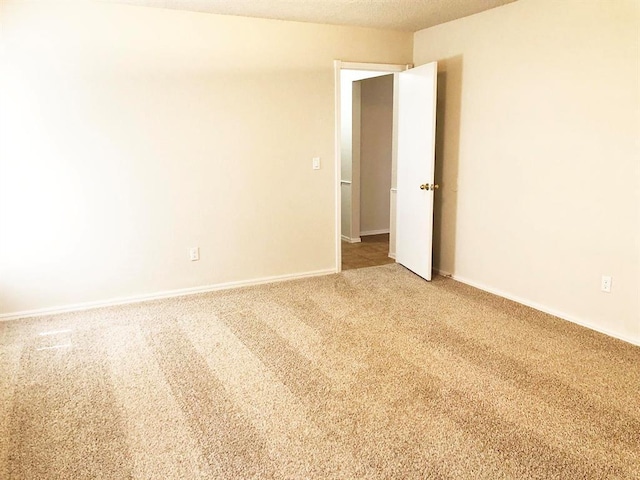 carpeted empty room with baseboards and a textured ceiling