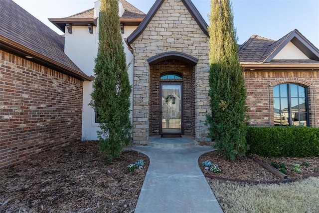 entrance to property with brick siding, stone siding, and stucco siding