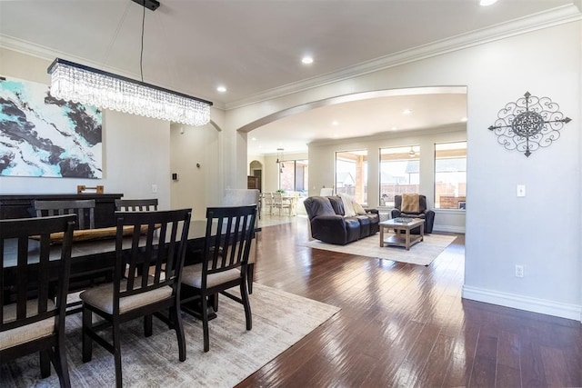 dining room featuring baseboards, arched walkways, ornamental molding, and hardwood / wood-style flooring