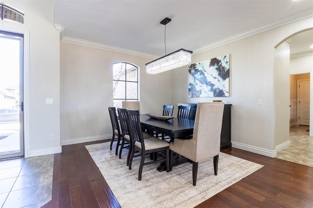 dining space featuring visible vents, wood finished floors, arched walkways, crown molding, and baseboards