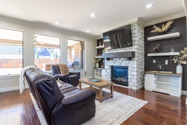 living area featuring a stone fireplace, crown molding, baseboards, and wood finished floors