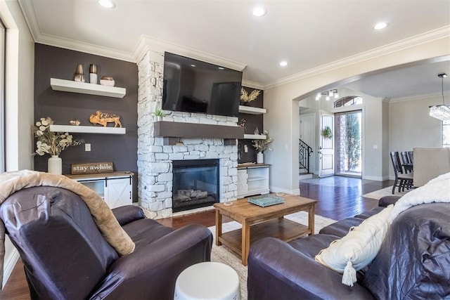 living room with arched walkways, ornamental molding, baseboards, and wood finished floors